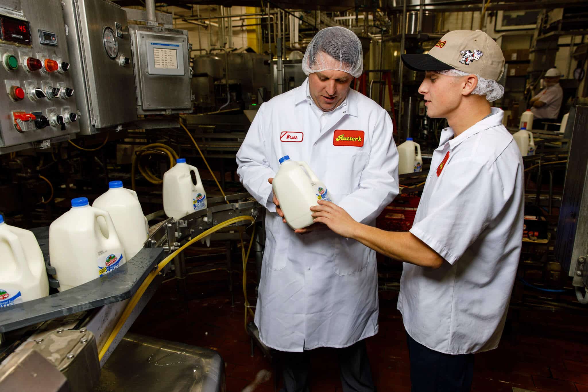 Men working on gallons of milk in a factory