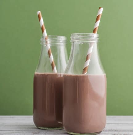 Two glass bottles filled with chocolate milk, each topped with a brown-striped straw.