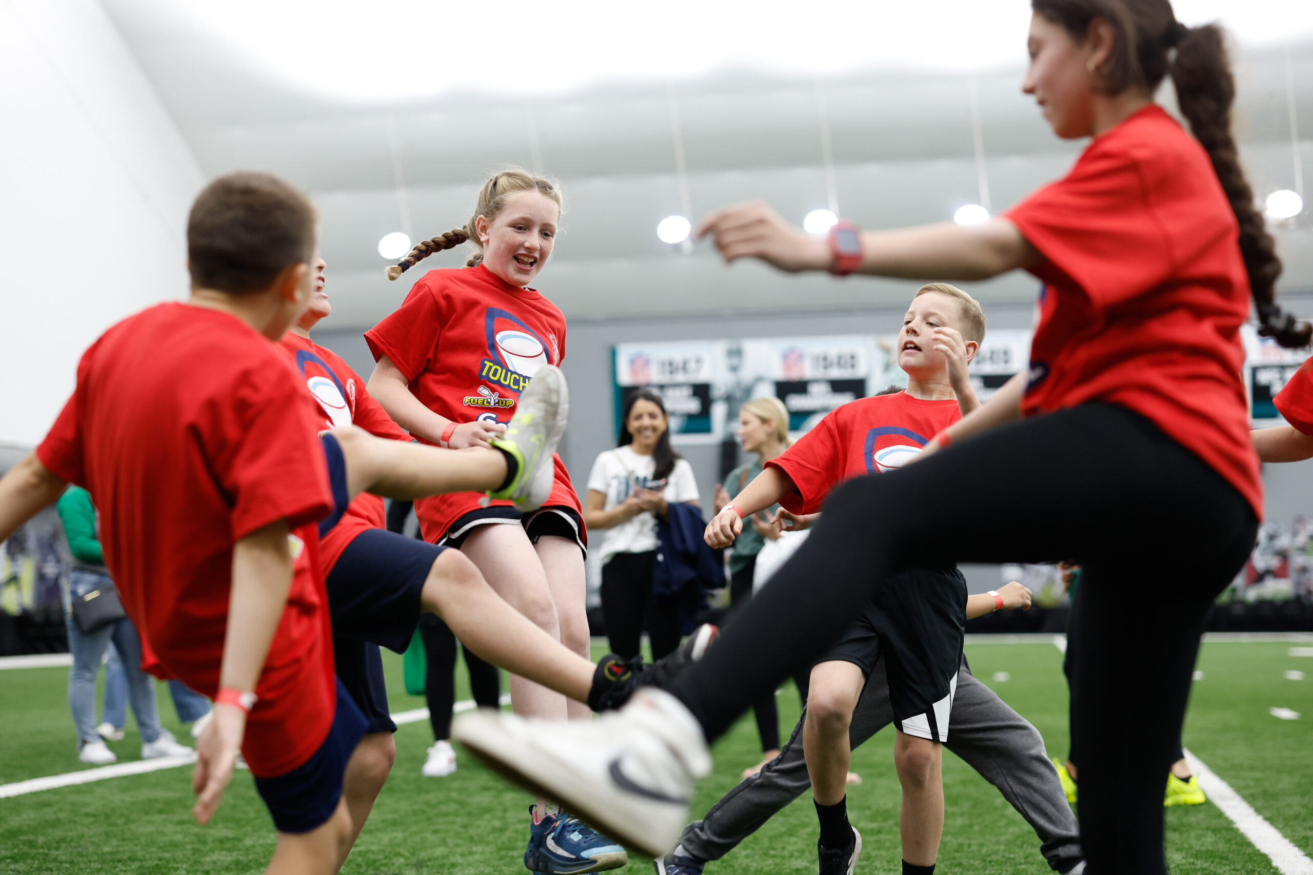 Children in orange t-shirts actively participate in activities at a Fuel Up event.