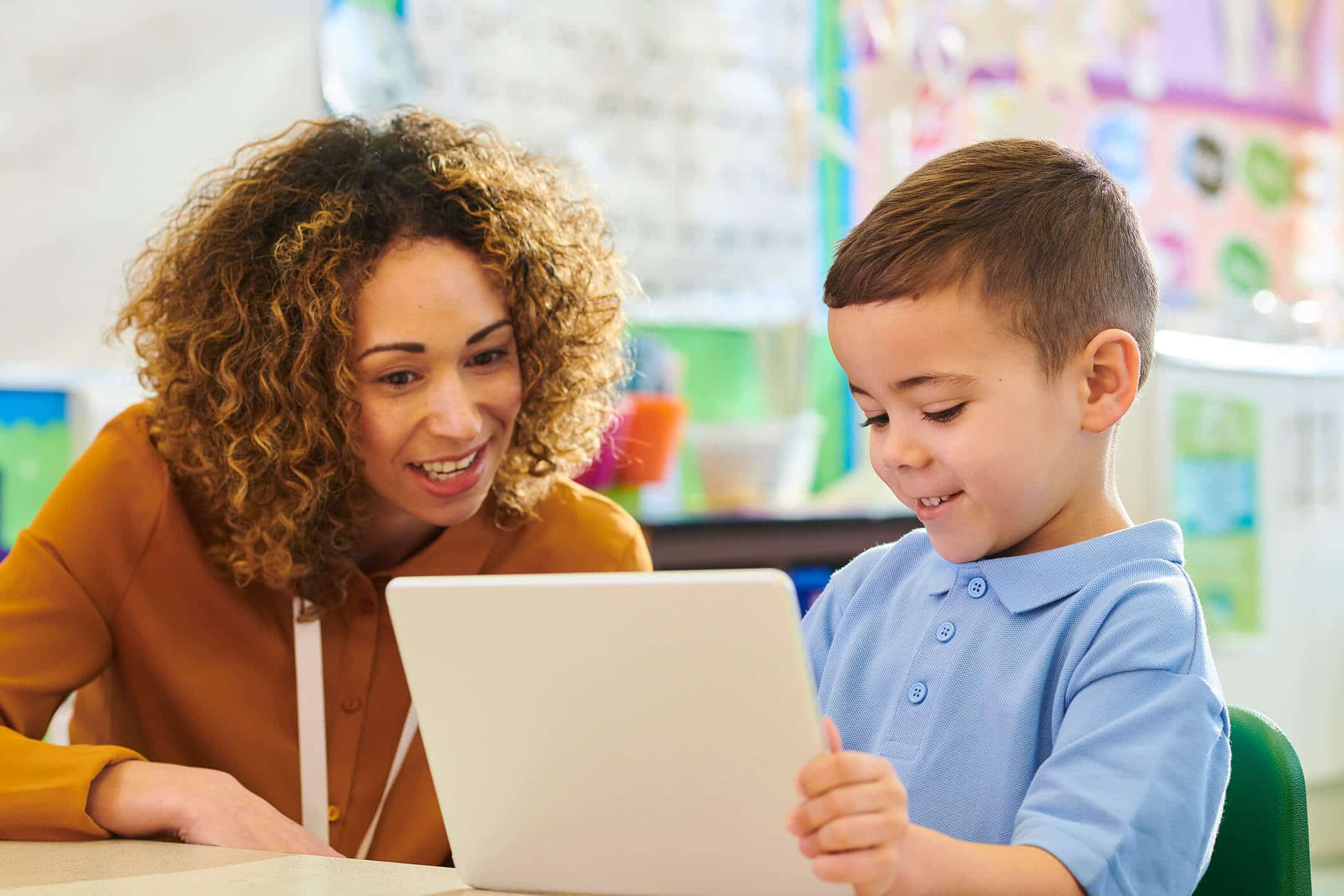 Teacher instructing a boy on a tablet