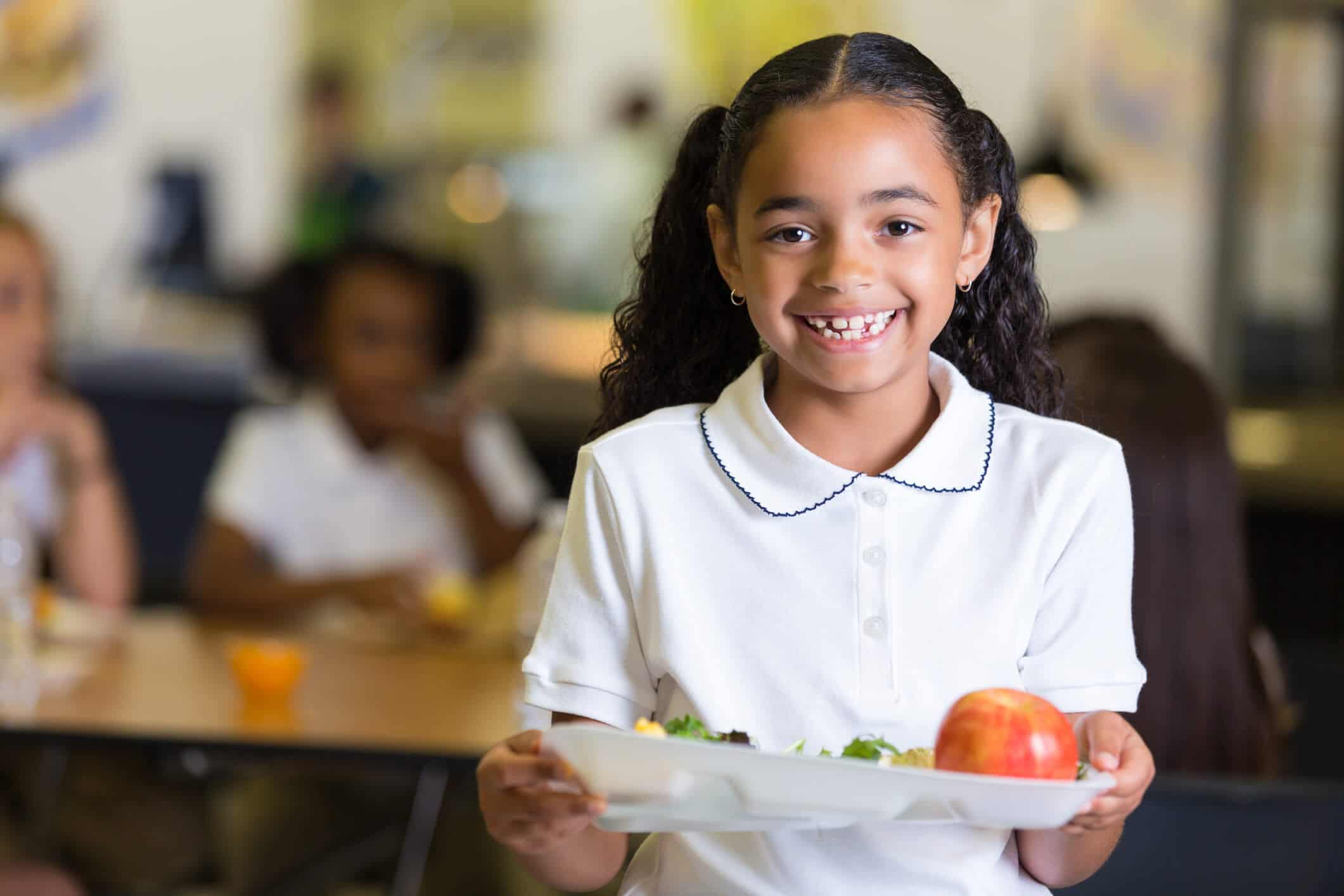 Girl smiling and holding a lunch tray