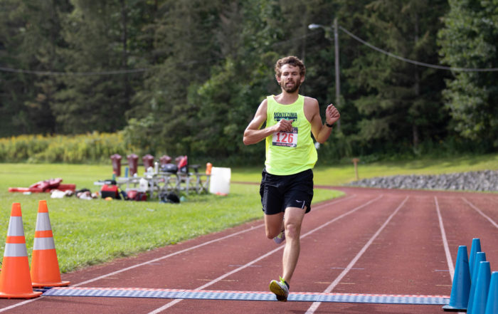 A dairy farmer runner clad in a yellow tank top trains on the running track.