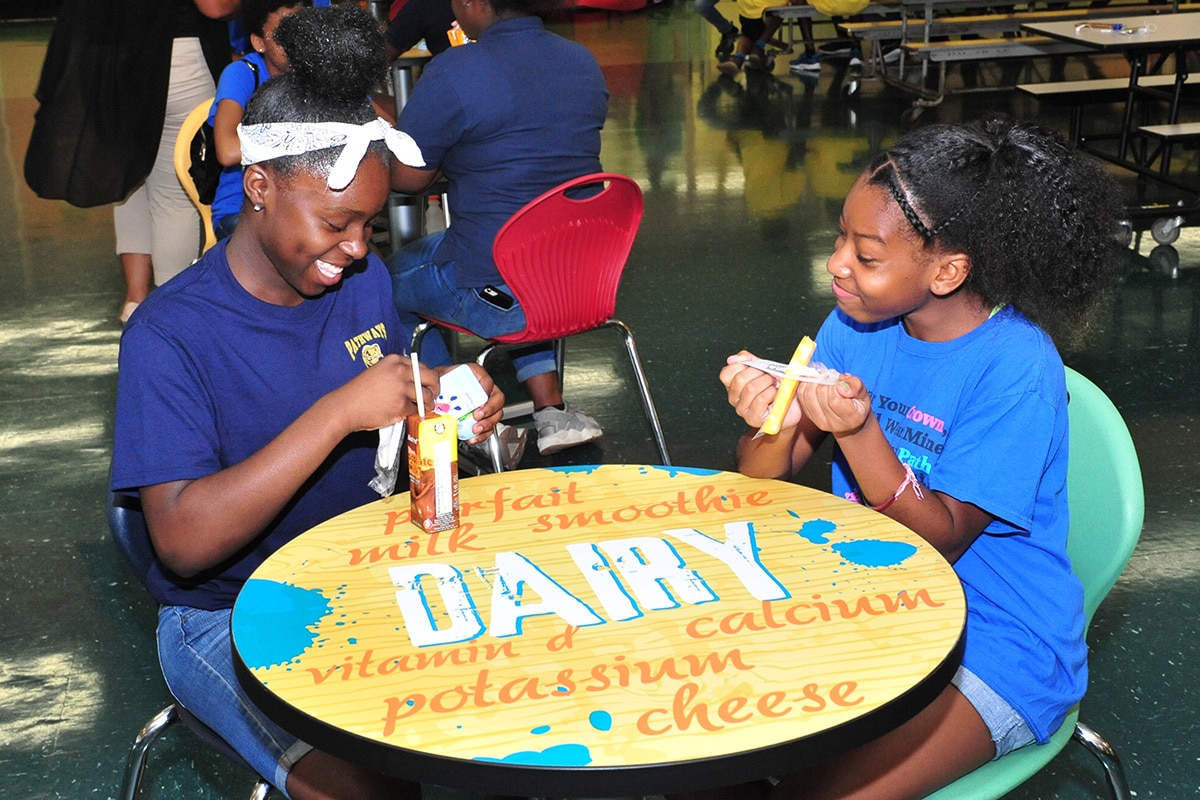 Two girls enjoying milk and cheese