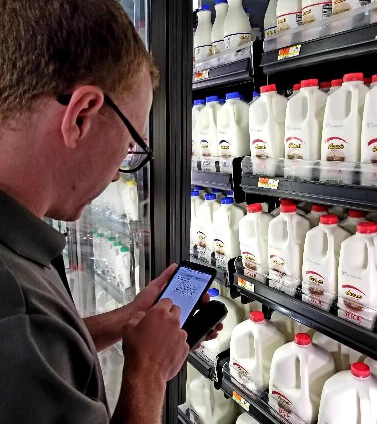 Man on his phone in front of milk in the dairy aisles