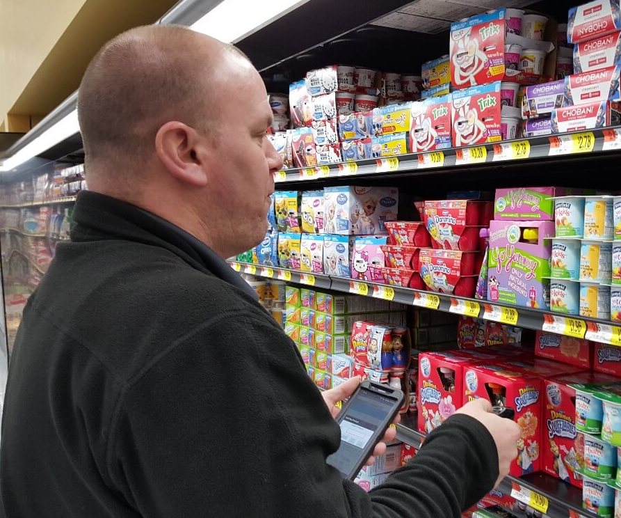 Man on his phone in front of yogurt in the dairy aisle