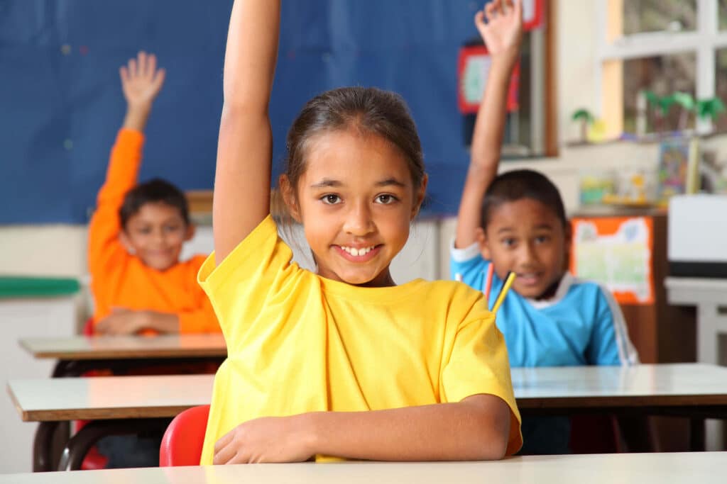 Students raising their hands in a classroom