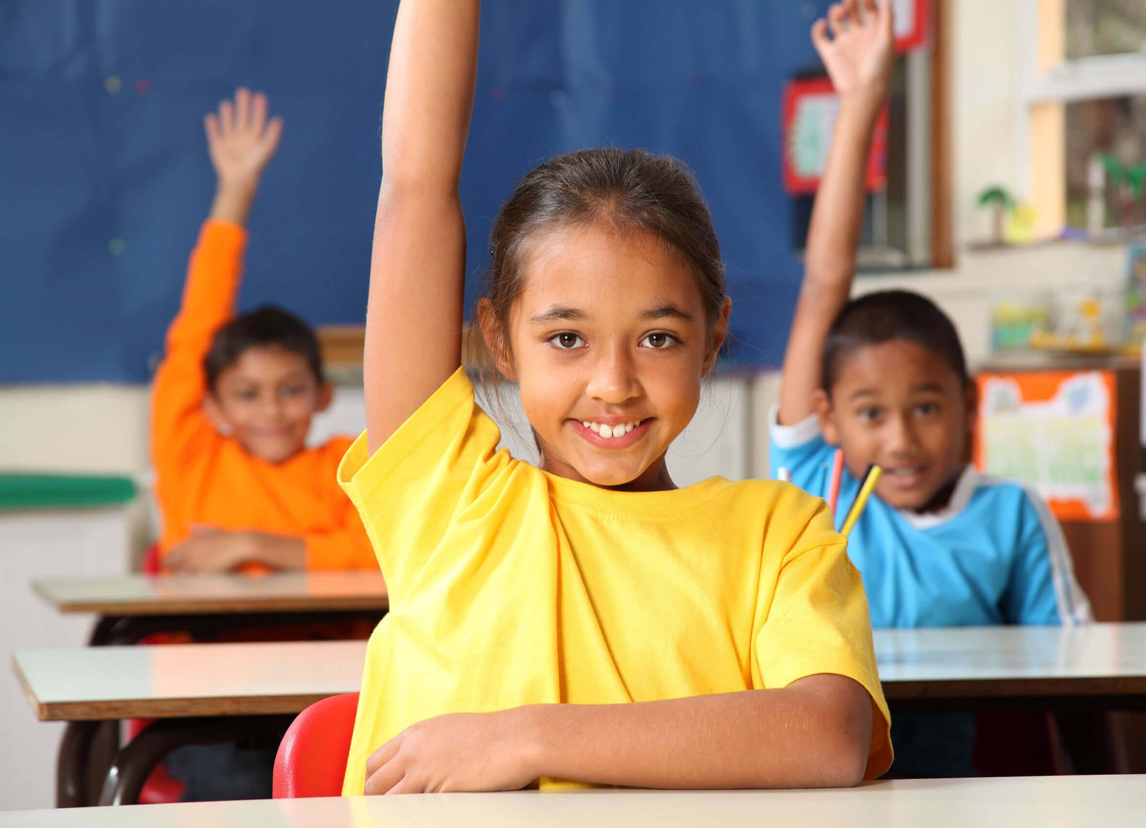 Students raising their hands in a classroom