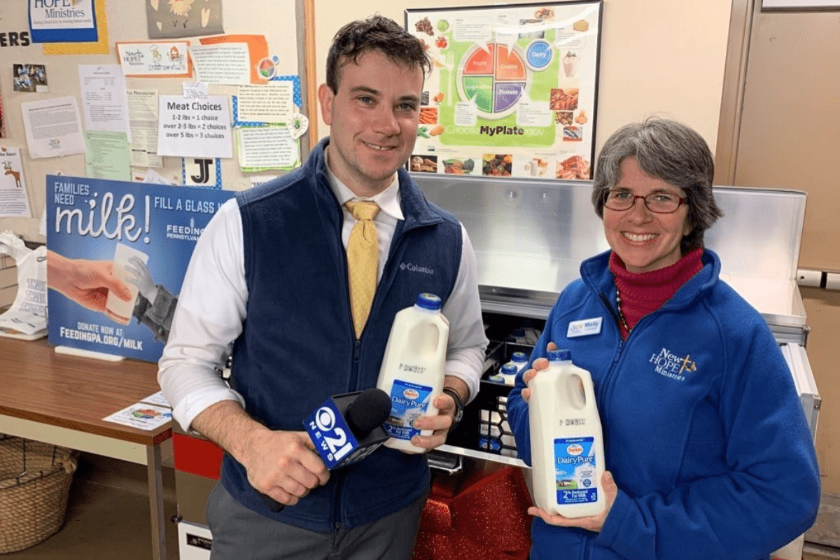 During an interview, a CBS journalist and a representative from New Hope Ministries are pictured holding milk bottles.