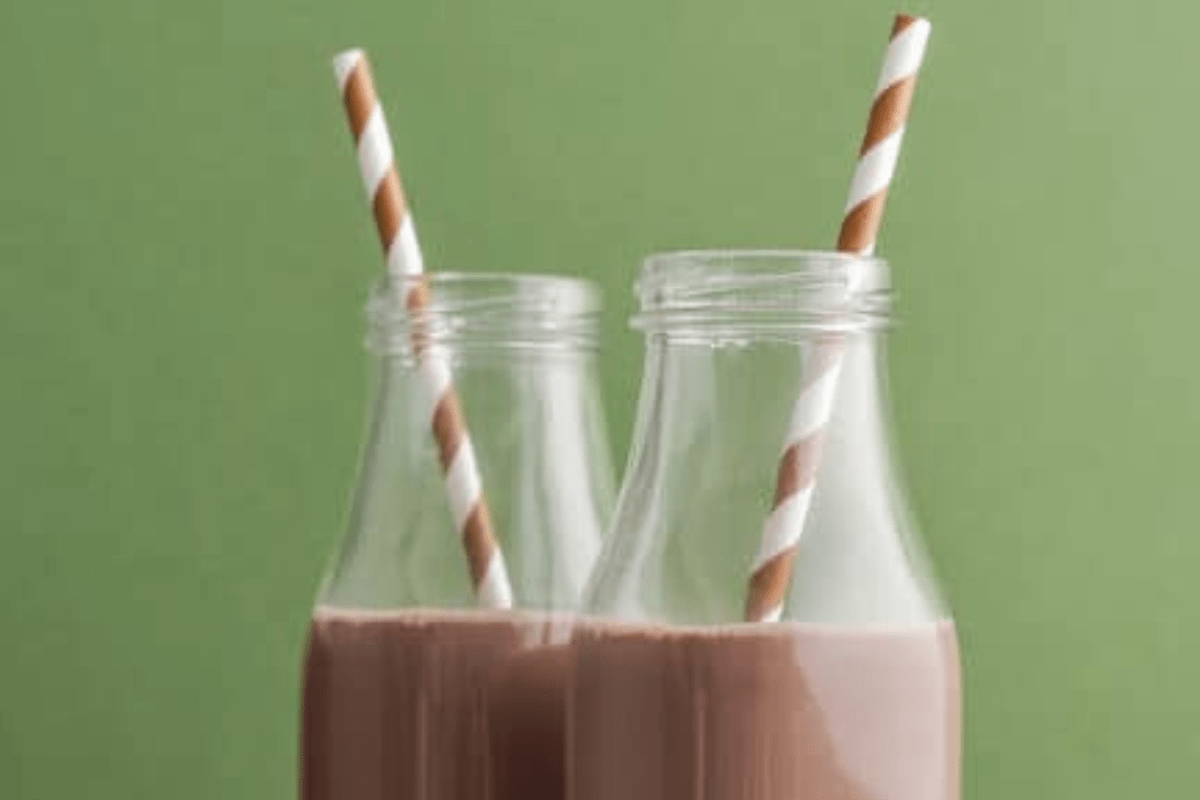 Two glass bottles filled with chocolate milk, each topped with a brown-striped straw.