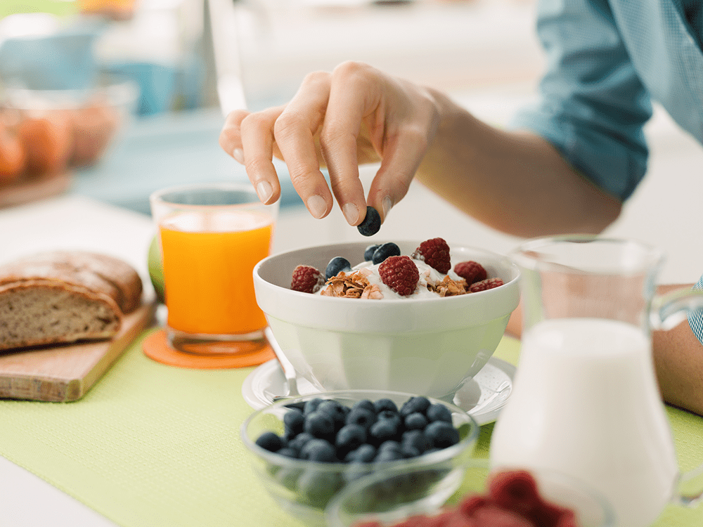 Woman putting berries in her yogurt