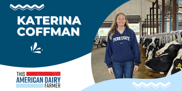 College student Katerina Coffman stands in front of a row of cows inside a barn.